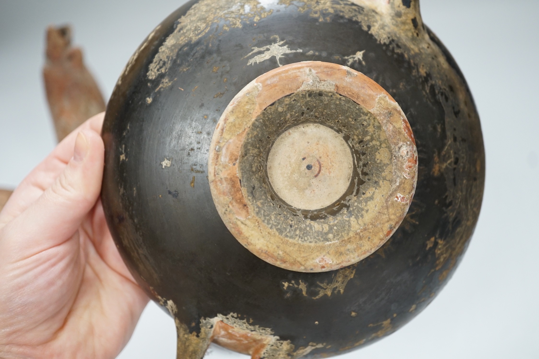 An Apulian black painted kylix, c. 4th century BCE., a Cypriot pottery flask, early Iron Age, two Roman terracotta oil lamps and another archaic vessel, tallest 14cm